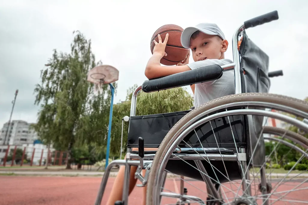 Disabled boy in wheelchair playing basketball