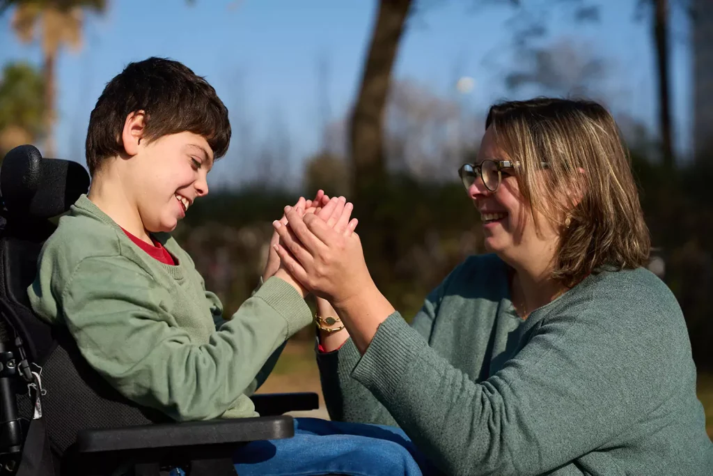 Disabled boy holding hands with support worker